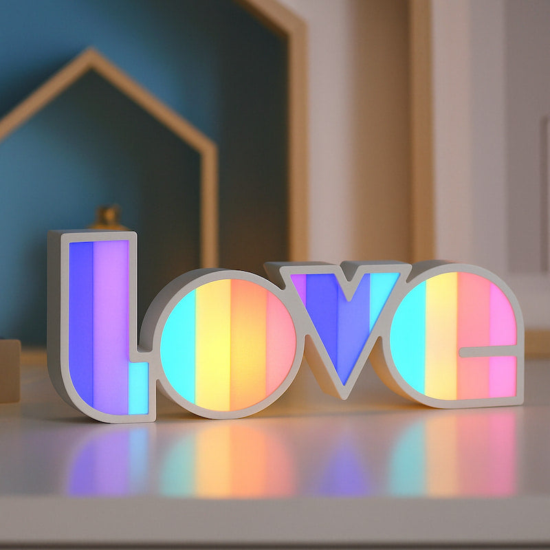 Veilleuse LOVE LED multicolore posée sur table de nuit